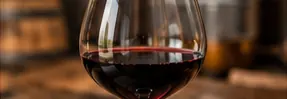 Glass of red wine on a wooden table in warm, low light